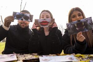 portrait of a group of people having fun showing a fantasy image partially covering their face in a public park in winter photo
