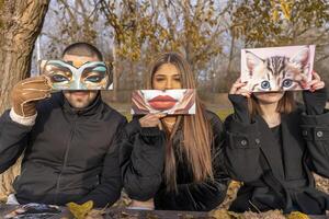 portrait of a group of people having fun showing a fantasy image partially covering their face in a public park in winter photo