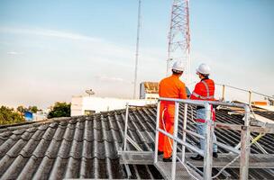 Two maintenance technicians and solar panel installers are planning to install solar cells on the roof of a building. photo