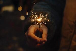 a group of people holding sparklers. Sparkler are thin sticks coated with a flammable substance that burns slowly, producing a shower of bright sparks. photo