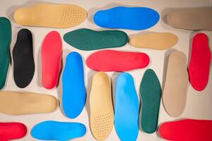Orthopedic insoles are lined up on a wooden surface. samples of different orthopedic insoles. insoles with a variety of coating. photo