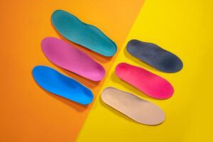 Orthopedic insoles are lined up on a wooden surface. samples of different orthopedic insoles. insoles with a variety of coating. photo