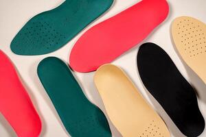 Orthopedic insoles are lined up on a wooden surface. samples of different orthopedic insoles. insoles with a variety of coating. photo