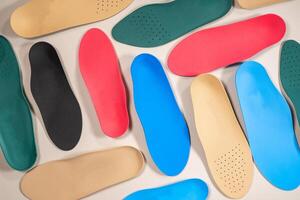 Orthopedic insoles are lined up on a wooden surface. samples of different orthopedic insoles. insoles with a variety of coating. photo