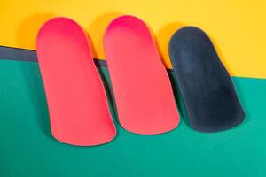 Orthopedic insoles are lined up on a wooden surface. samples of different orthopedic insoles. insoles with a variety of coating. photo