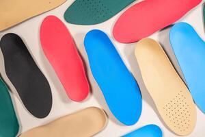 Orthopedic insoles are lined up on a wooden surface. samples of different orthopedic insoles. insoles with a variety of coating. photo