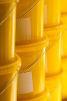 Many yellow color buckets cans in a row with ink paint row photo