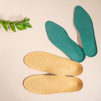 Orthopedic insoles are lined up on a wooden surface. samples of different orthopedic insoles. insoles with a variety of coating. photo