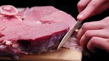 A butcher removes the fascia from a beef steak with a large knife in a dark room video
