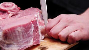 A butcher removes the fascia from a beef steak with a large knife in a dark room video