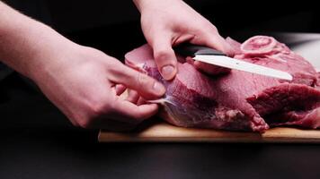 A butcher removes the fascia from a beef steak with a large knife in a dark room video