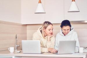 Two women talk and smile, discuss an online presentation, work on a joint project, share ideas during teamwork photo