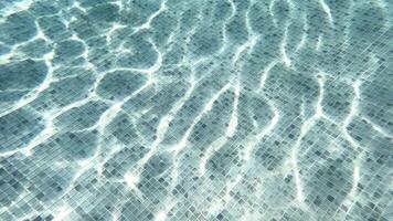 Abstract blue color water in swimming pool, pure natural swirl pattern texture. Top view of a blue calm, clear water surface, texture with ripples and shadow. Summer banner concept, backdrop video
