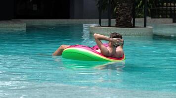 Back view of man floats in the pool with an inflatable ring, enjoying a moment of relaxation. This scene embodies the spa concept, perfect for themes of leisure and wellness. video