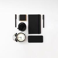 Trendy arrangement made with black notebooks, pens, alarm clock and phone on white background. Minimal business concept. Creative office objects idea. Black and white flat lay. photo