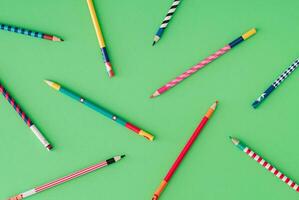 Creative colorful pattern made of colored pencils on pastel green background. Minimal school concept. Trendy coloured pencils aesthetic art pattern idea. Flat lay backdrop image. photo