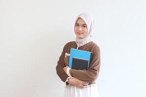 Portrait of a Smiling Muslim Woman Student Holding Books Against White Background photo