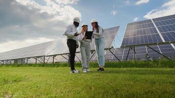 Group of three multiracial engineers at solar station checking solar panels setup video