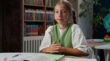Doubtful confused Caucasian little girl child kid schoolgirl uncertain insecure school student pupil learner doing homework studying learn education looking camera shrugging shoulders gesture indoors video