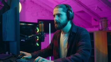 Carefree Caucasian male gamer blogger vlogger man playing computer game cyber sport gaming blog stream radio microphone broadcast addicted at home e-sport influencer laugh smiling guy typing keyboard video