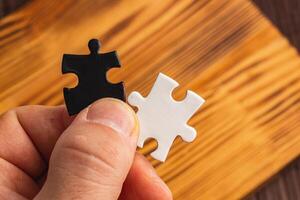 Hands holding black and white puzzle, concept of difficult option choice photo