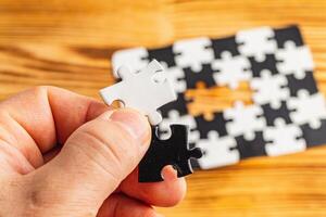 Hands holding black and white puzzle, concept of difficult option choice photo