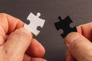 Hands holding black and white puzzle, concept of difficult option choice photo