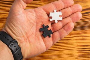 A hand holding two puzzle pieces one white and one black, difficult choice photo