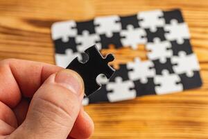 Hands holding black and white puzzle, concept of difficult option choice photo