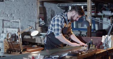 Male artisan rolling leather in workshop video