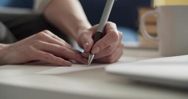 Cropped student taking notes in notebook at home video