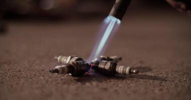 Anonymous technician using blowtorch on spark plugs video