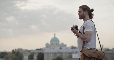 Bearded tourist capturing moment on retro camera during trip video