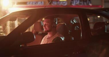Man sitting in automobile late at night and enjoying music video