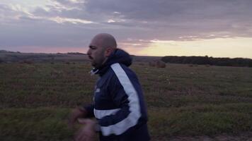 Man in sportswear running in sundown time near agriculture fields video