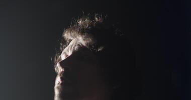 Male guitarist starting performance in dark studio with white illumination video