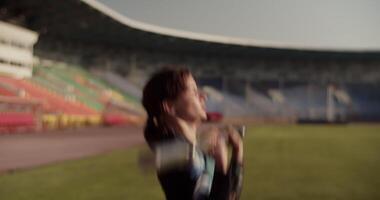 Strong female athlete exercising with barbell at stadium video