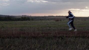 Sportsman running in field with haystacks in evening video