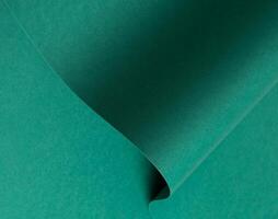 Emerald green paper background with a matte finish and subtle wavy texture. Deep green tones create photo