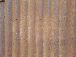 a close-up view of a textured surface a metal sheet, with a dull grayish tone. The surface features a mix of light and dark patches, creating a mottled, weathered, or oxidized appearance photo