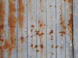 a close-up view of a textured surface a metal sheet, with a dull grayish tone. The surface features a mix of light and dark patches, creating a mottled, weathered, or oxidized appearance photo