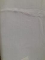 a close-up view of a light-colored fabric surface. The texture appears soft and smooth, with subtle creases and wrinkles running horizontally across the material. photo
