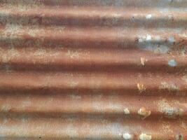 a close-up view of a textured surface a metal sheet, with a dull grayish tone. The surface features a mix of light and dark patches, creating a mottled, weathered, or oxidized appearance photo