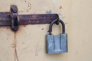 A rusty padlock hangs from a uniquely designed yellow door, symbolizing abandonment and security photo