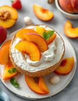 Delicious coconut bowl filled with whipped cream and fresh peach slices on a marble surface photo