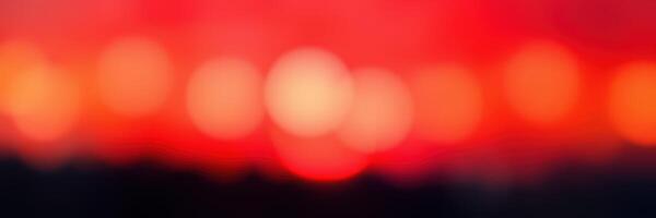 Sunset creates vibrant bokeh of red and orange hues over a tranquil landscape with glowing lights photo
