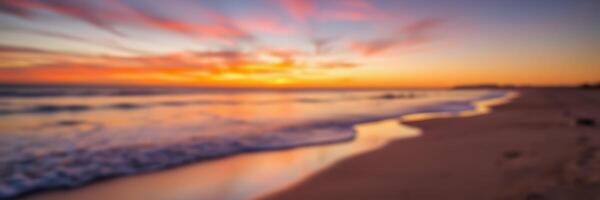Vibrant sunset reflects on calm ocean waves at a serene beach during twilight photo