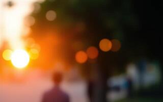 Golden sunset light creates a warm atmosphere as people walk along a tree-lined street in the evening photo