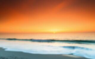 Colorful sunset over the ocean waves with soft reflections on the sandy beach photo