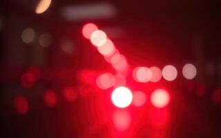 Colorful bokeh lights illuminate a city street during nighttime with a vibrant red hue creating an abstract urban landscape photo